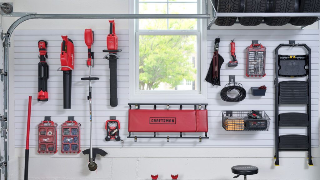 a garage slatwall system with lots of tools hanging on it .