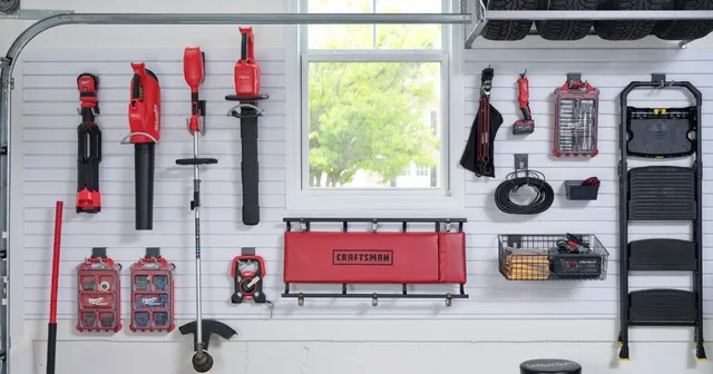 a garage slatwall system with lots of tools hanging on it .