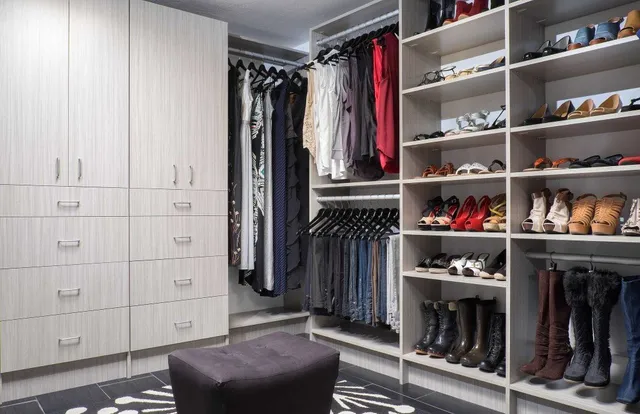 A walk in closet filled with lots of clothes and shoes .